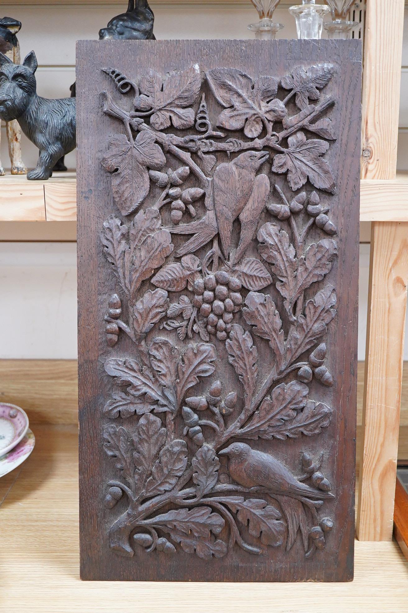 A carved oak relief panel, of acorns, oak leaves and a bird, 64cm high, 33cm deep